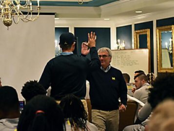 Coach Harbaugh and Jim Burnstein give each other a "high five" after a meaningul merging of departments  